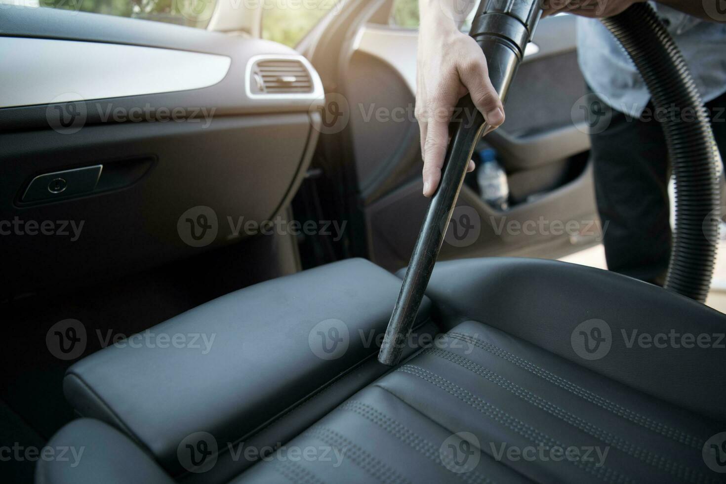 hombre utilizando coche vacío limpiador a ordenado coche. foto