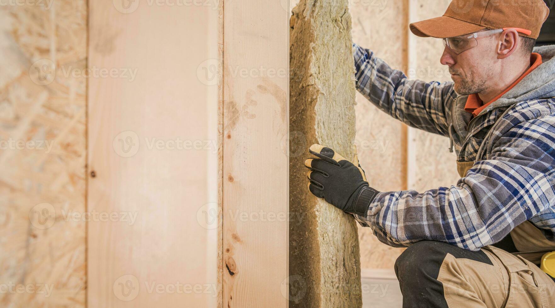 trabajador aislante casa paredes con pedazo de mineral lana foto
