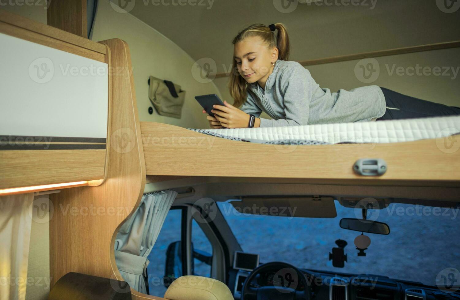 Girl Hanging on Bunk Camper Bed with Her Smartphone photo