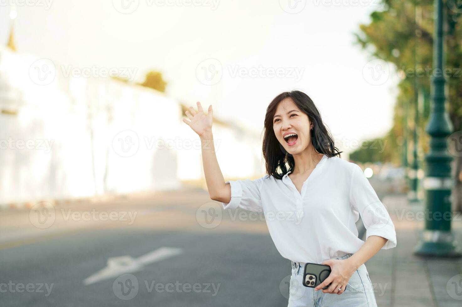 Portrait young beautiful asian woman waving hand to friend by the street in sunny holiday. photo