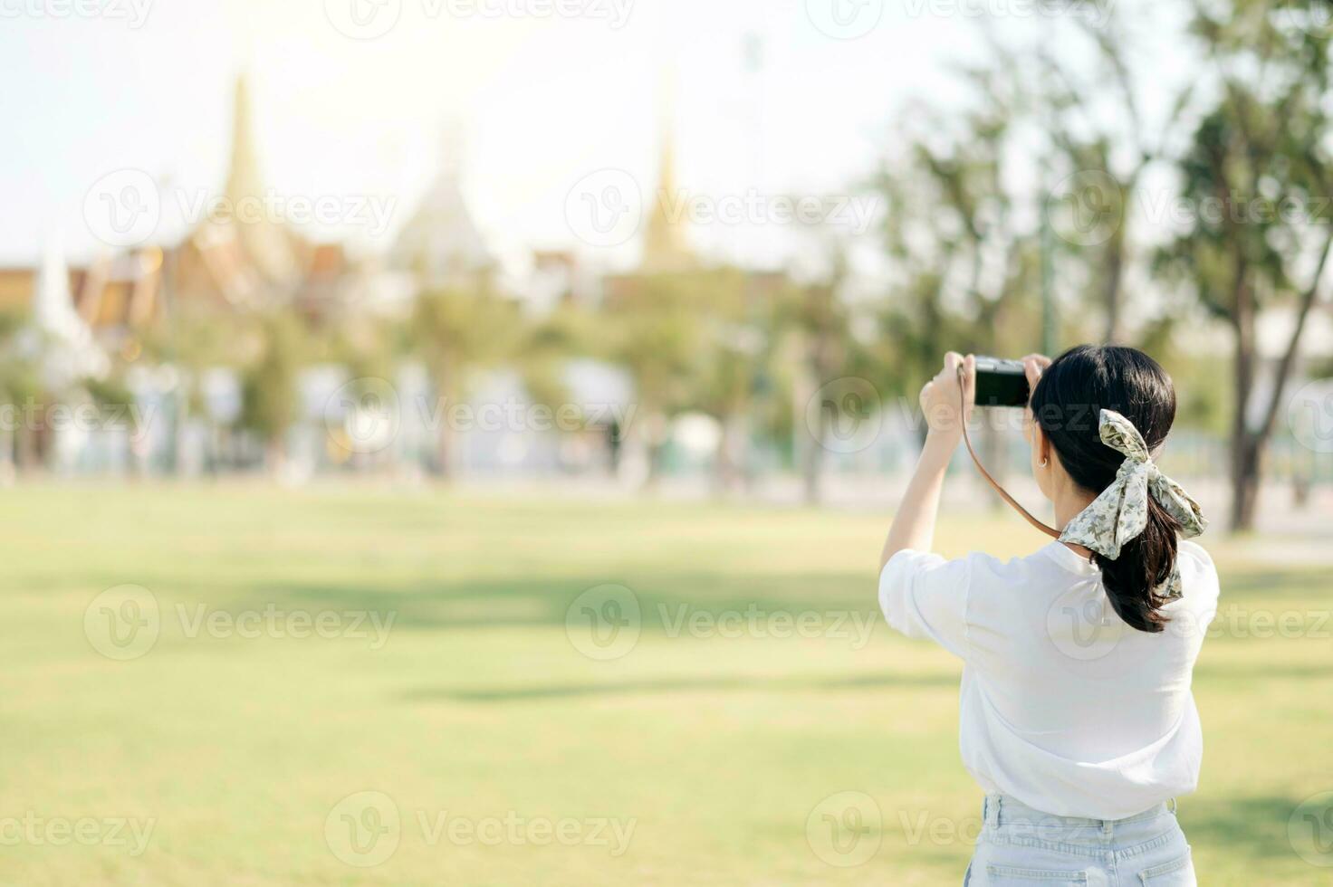 Portrait of asian woman traveler using camera. Asia summer tourism vacation concept with the grand palace in a background at Bangkok, Thailand photo