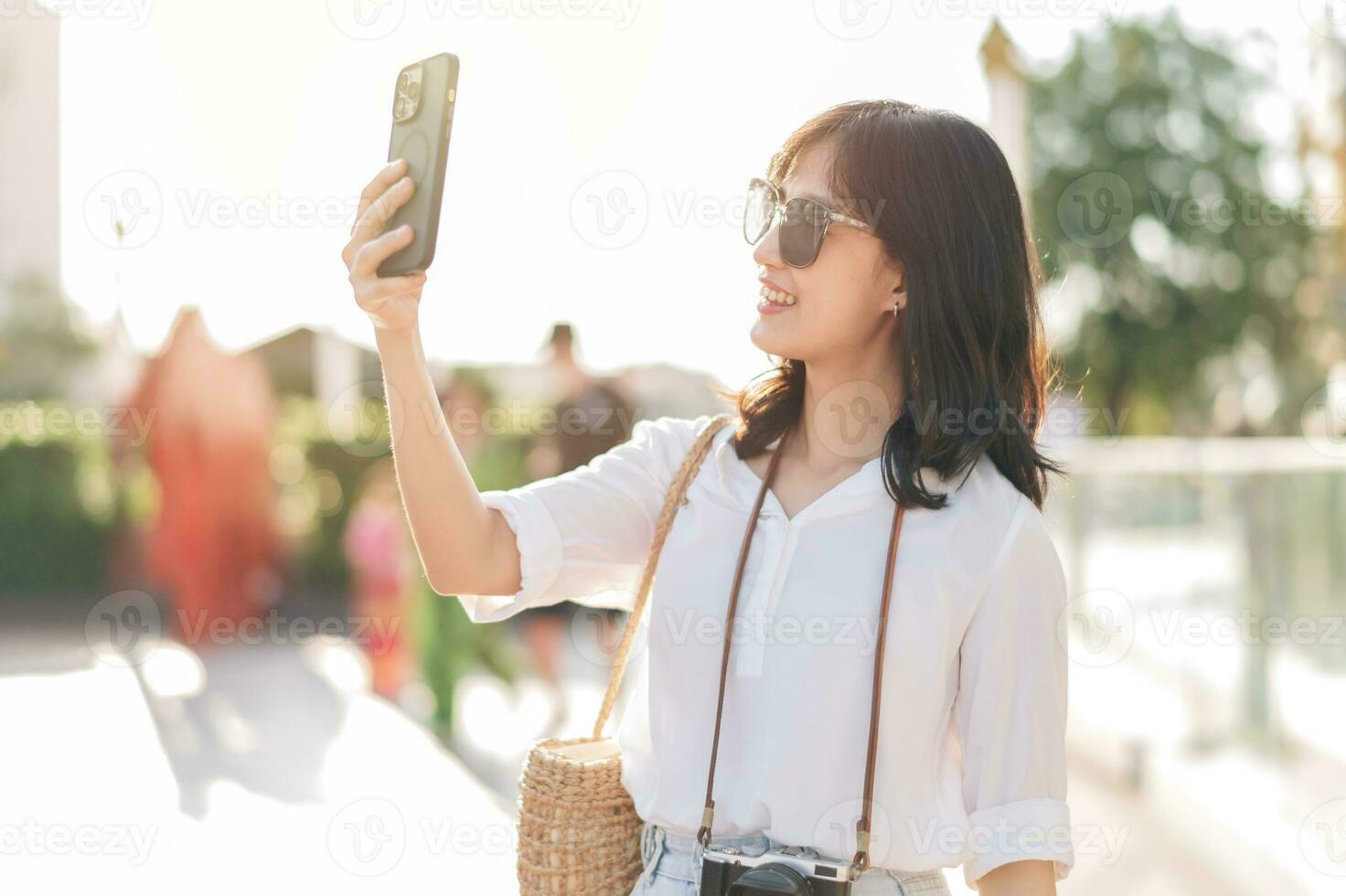 Portrait young beautiful asian woman using smartphone to video call with friend and explore street on summer vacation in Bangkok, Thailand photo