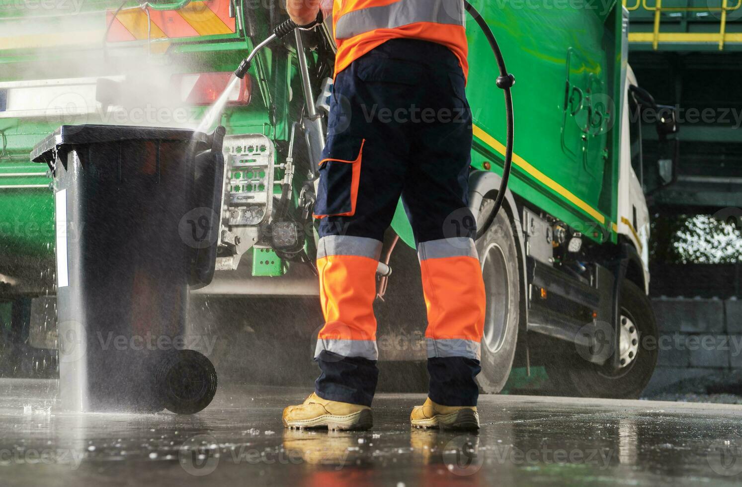 Garbage Truck Operator Pressure Washing Black Trash Can photo