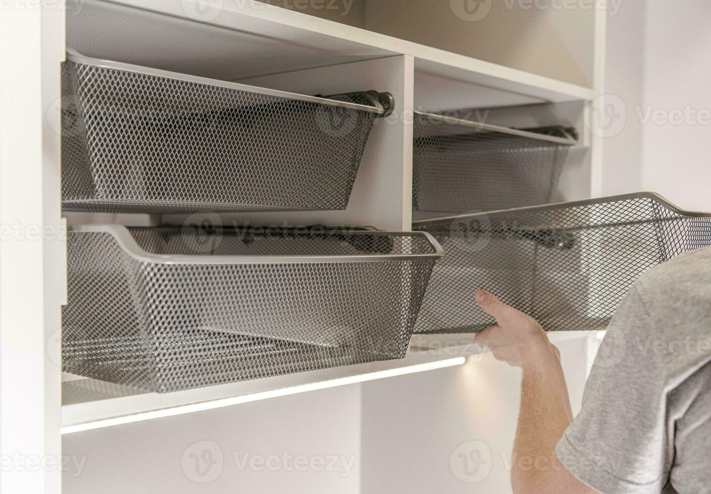Close Up Of Handyman Installing Storage Wire Baskets In Closet. photo