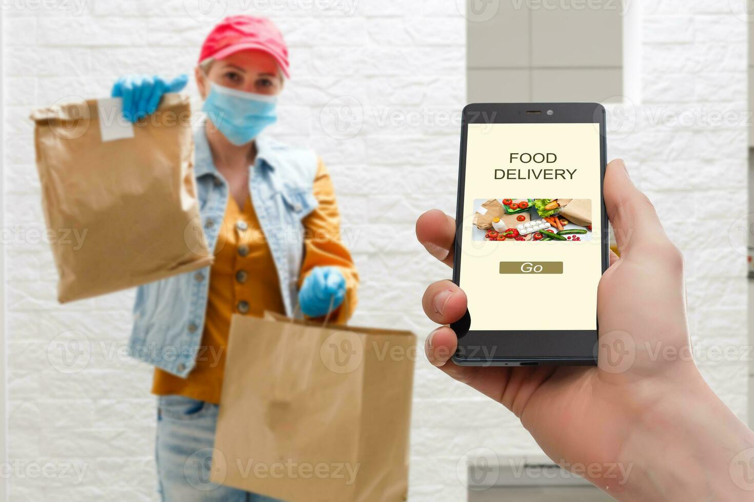 delivery food service at home. Man courier delivered the order no name bag with food. Hand holding smart phone with food online device on screen photo