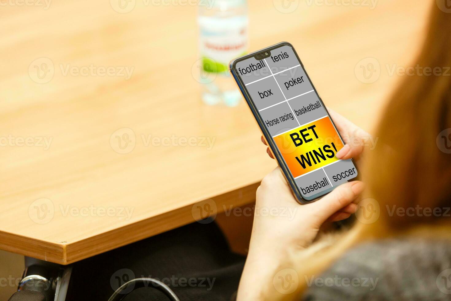 Close up cropped shot of female hands holding smartphone with bookmaker's website on a screen. Young woman placing sport bets online using mobile application. photo