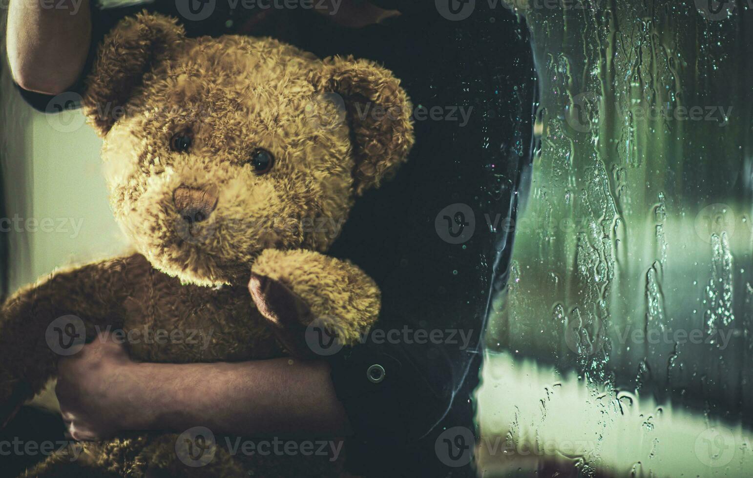 Child With Teddy Bear Sitting On Windowsill At Night. photo