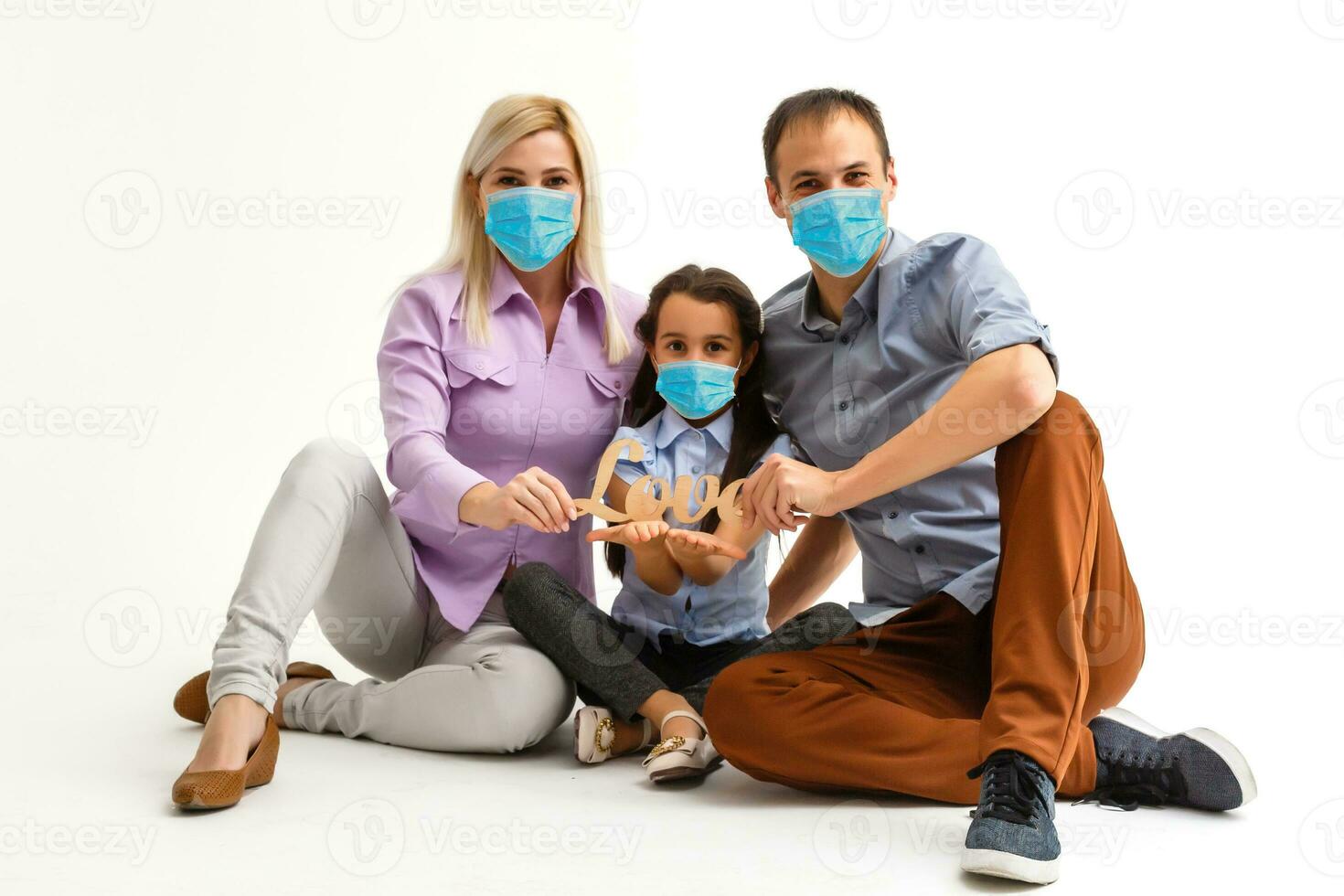 family in protective masks quarantined. Normal life with coronavirus. Lifestyle COVID-19. Quarantine virus protection sterility home together heart symbol photo