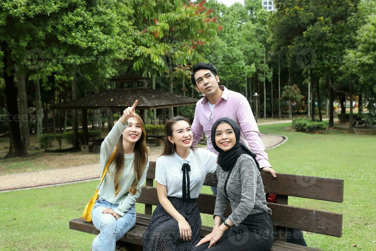 Young asian malay chinese man woman outdoor on park bench mingle talk discuss happy point photo