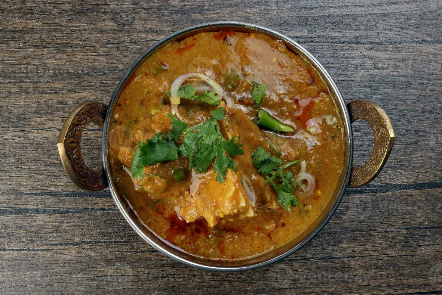 Haleem stew wheat barley lentils mutton goat chicken beef meat bone spice served in a copper brass pot over rustic wood background photo