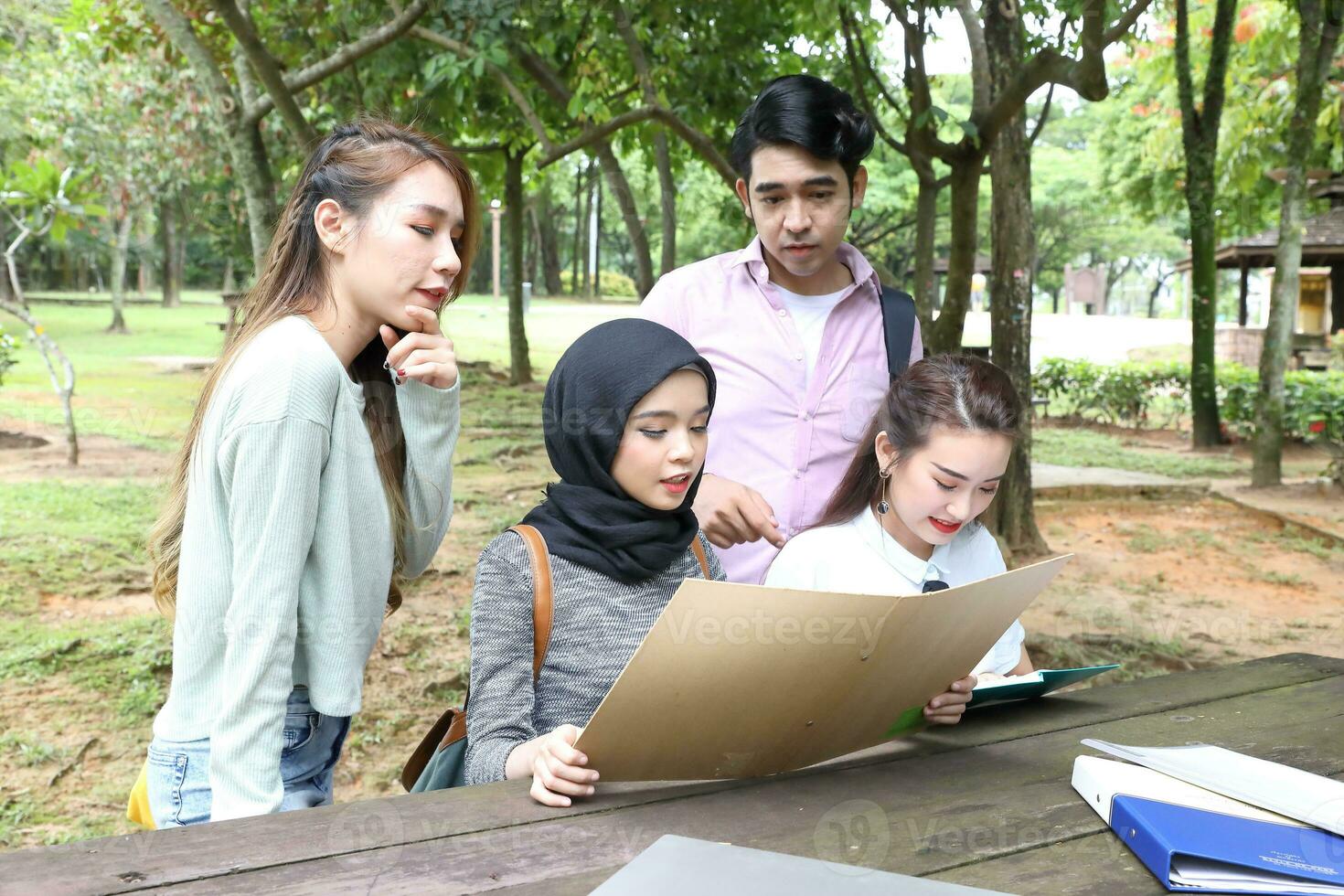 Young asian malay chinese man woman outdoor park  book file folder laptop computer phone sit stand study mingle photo