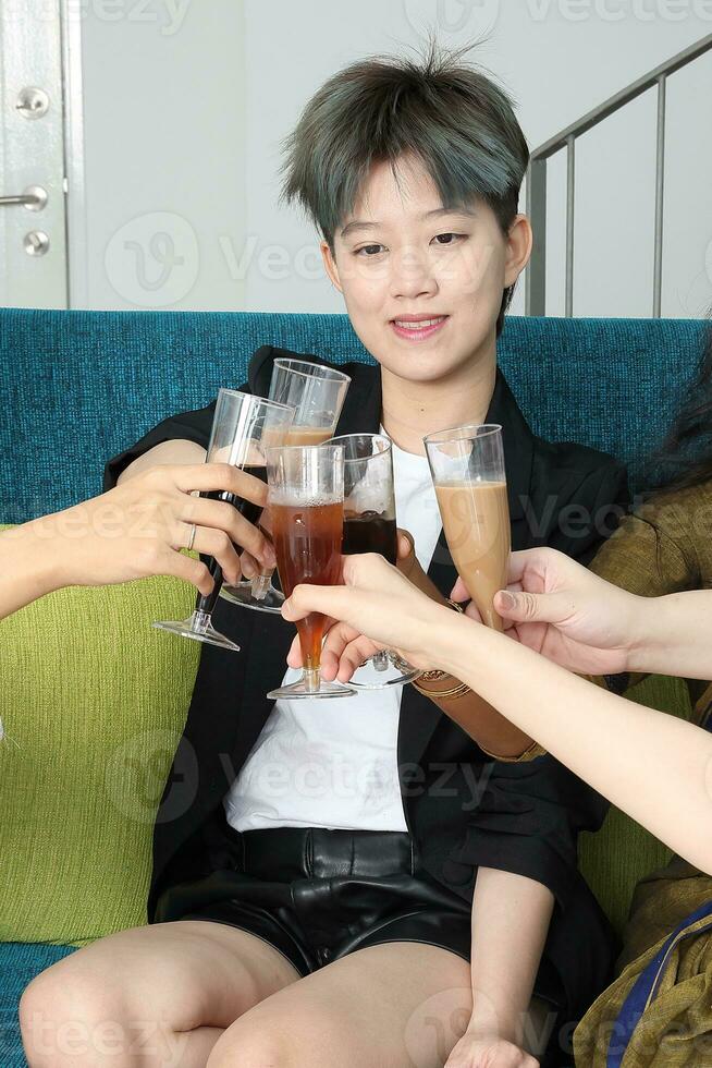 Young southeast asian woman group talk celebrate sing making funny mocking faces expression drinking cheering cheers on blue living room sofa photo