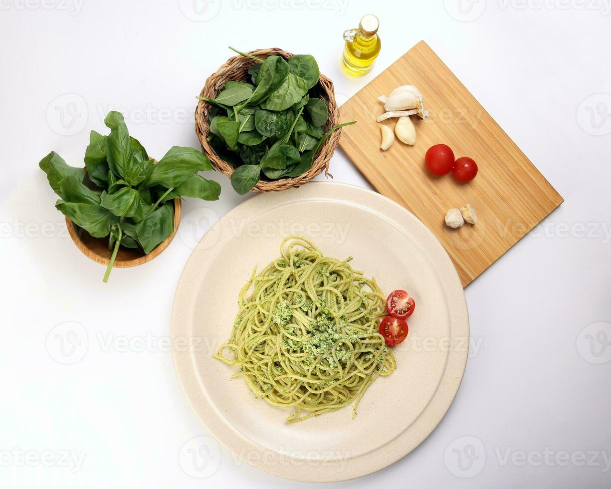 Asian style spaghetti with minced chicken spinach thai basil tomato garlic nutmeg olive oil presto sauce served on badge ceramic plate over on white background ingredients wooden board bowl photo