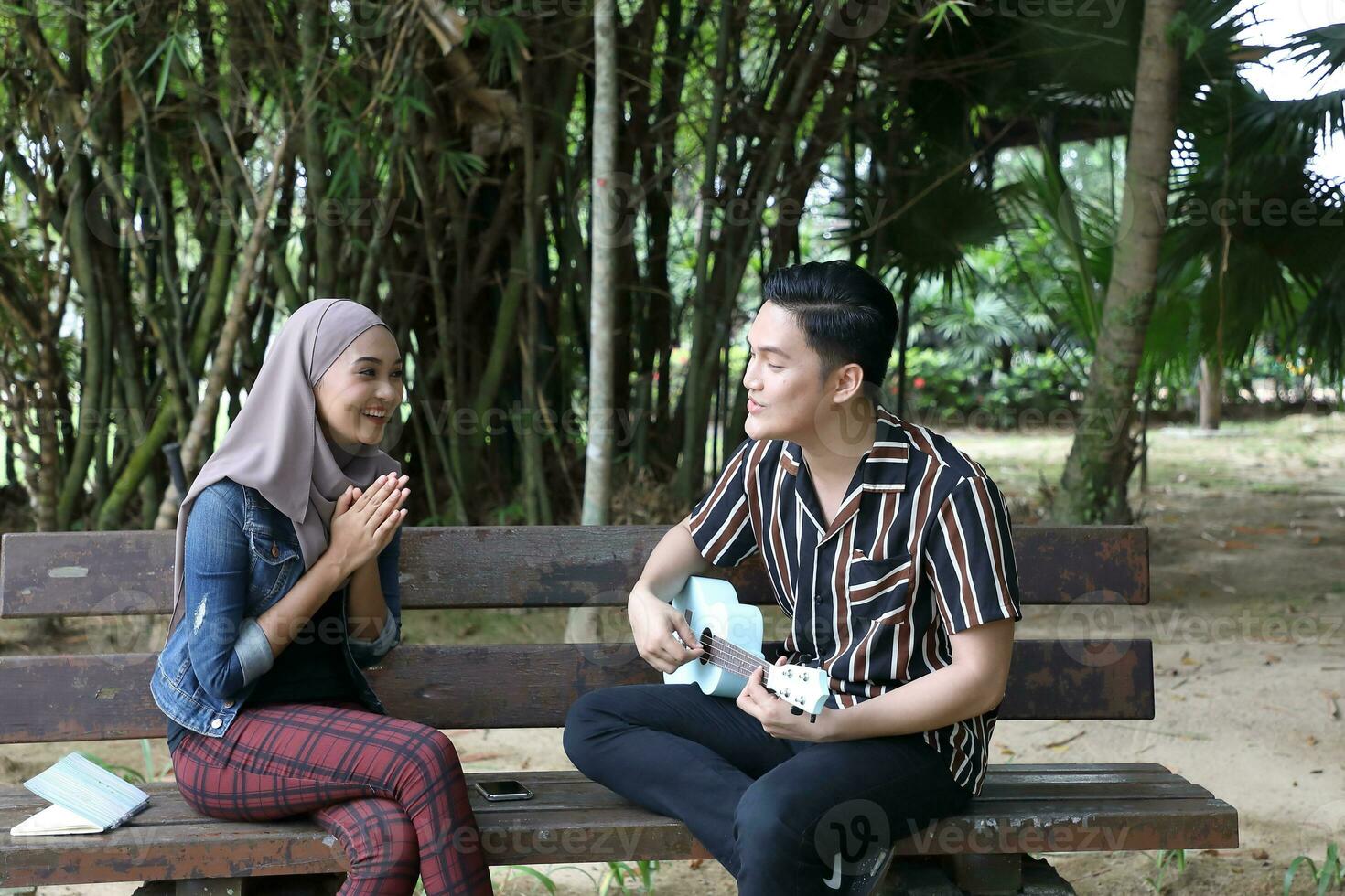 Young Asian Malay man woman outdoor green park walk talk discuss mingle photo