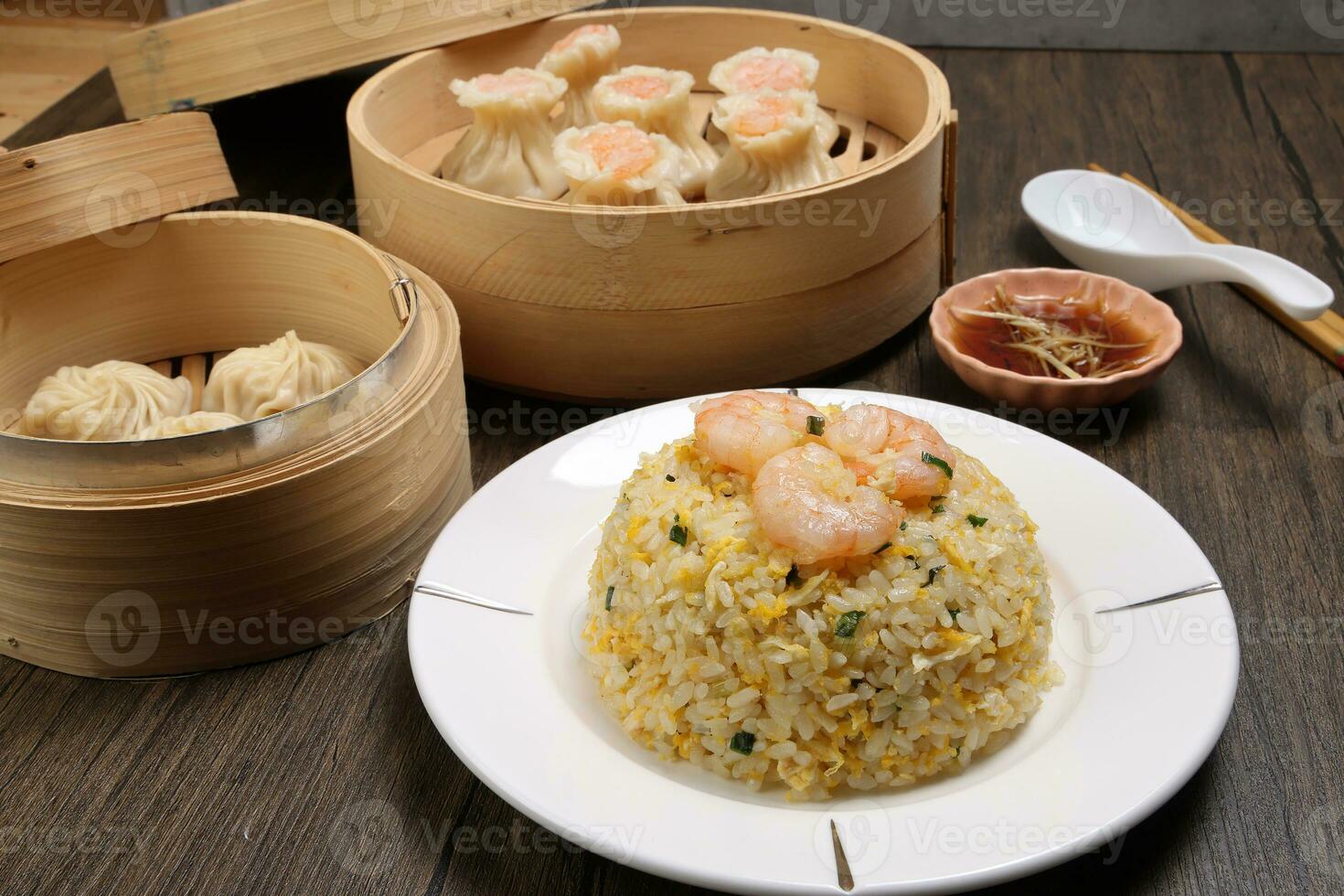 Prawn shrimp shaomai Xiao long bao dim sum dumpling chicken prawn fish seafood vegetable in bamboo steamer fried rice on plate sauce chopsticks soup spoon over rustic background photo