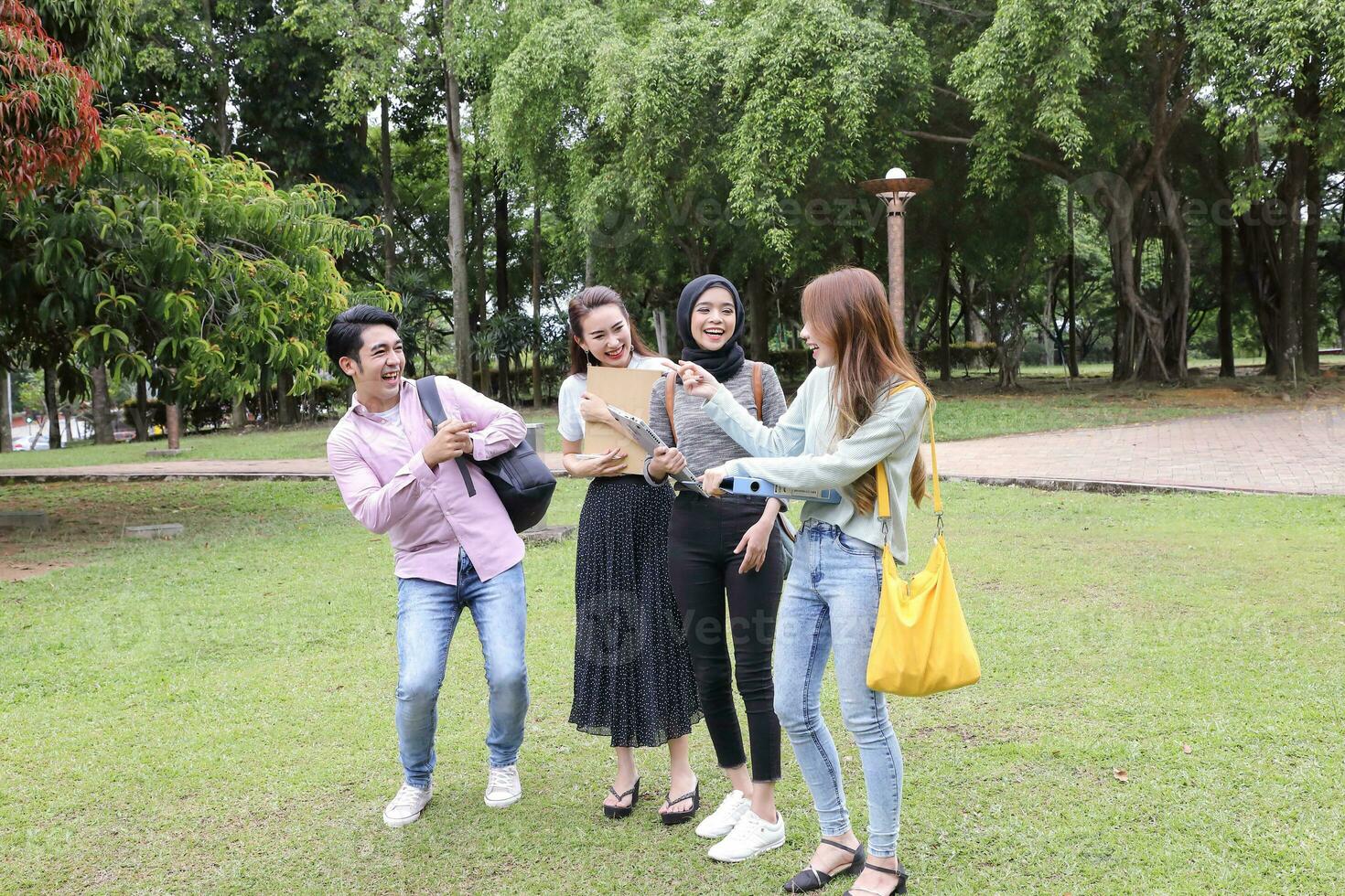 Young asian malay chinese man woman outdoor park walk stand study talk discuss point laptop file book backpack photo