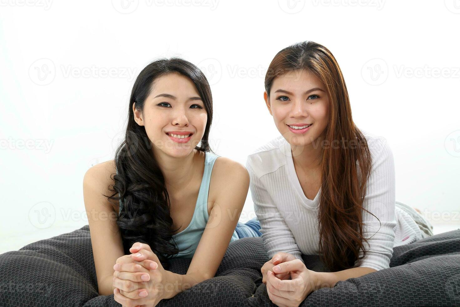 Two Beautiful young south east Asian Chinese relax pillow cushion look at camera on white photo