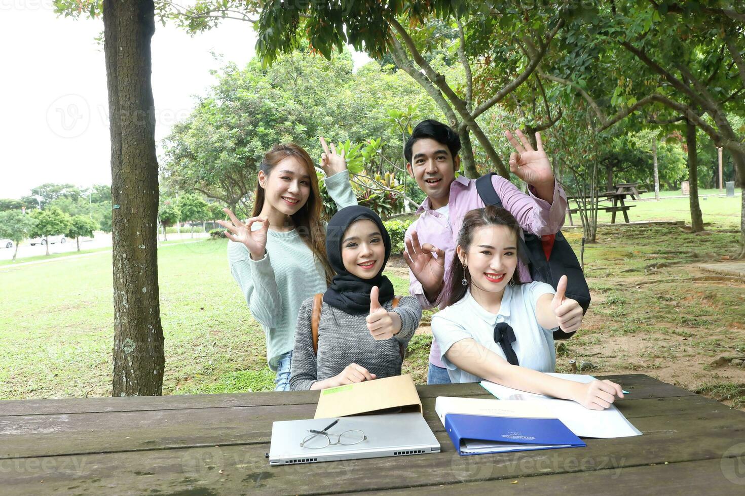 Young asian malay chinese man woman outdoor park  book file folder laptop computer phone sit stand study mingle photo