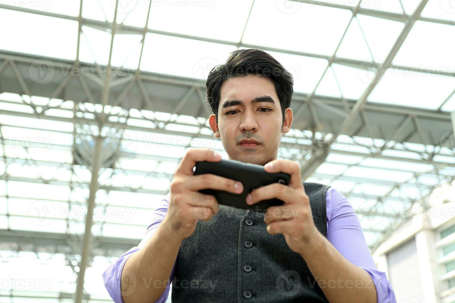 Southeast Asian young office business man wearing vest text use smart phone at outdoor premises photo