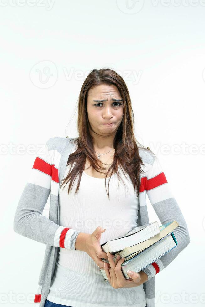 Yong Asian youth girl in casual dress carrying heavy book look at camera funny face expression difficult on white background photo