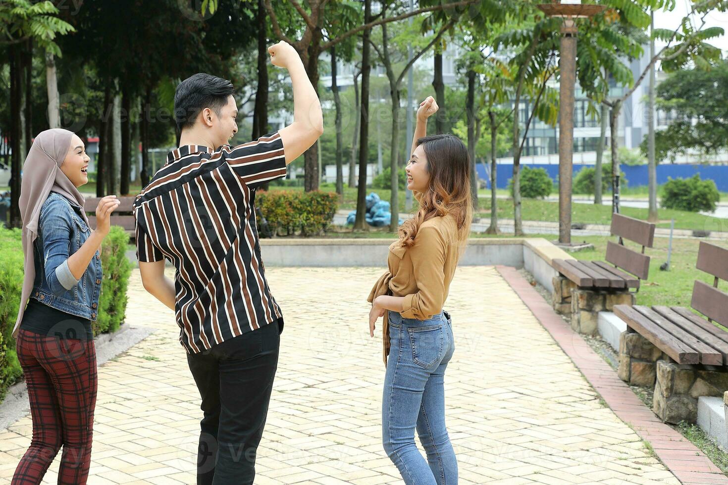 Young Asian Malay man woman outdoor green park walk talk discuss mingle sign show photo