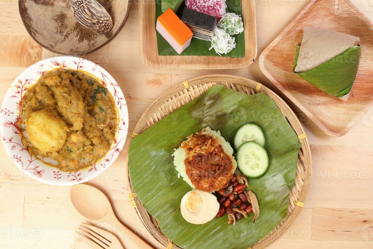 Nasi Lemak fragrant rice coconut milk with sambal friend peanut anchovy egg packed banana leaf round bamboo plate colorful nyonya kuih sweet desert palm leaf plate on wooden background photo