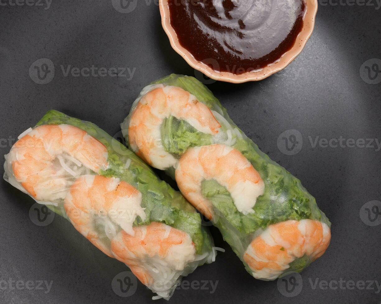 Vietnamese prawn shrimp see through rice paper spring roll green vegetable sauce on dark plate photo
