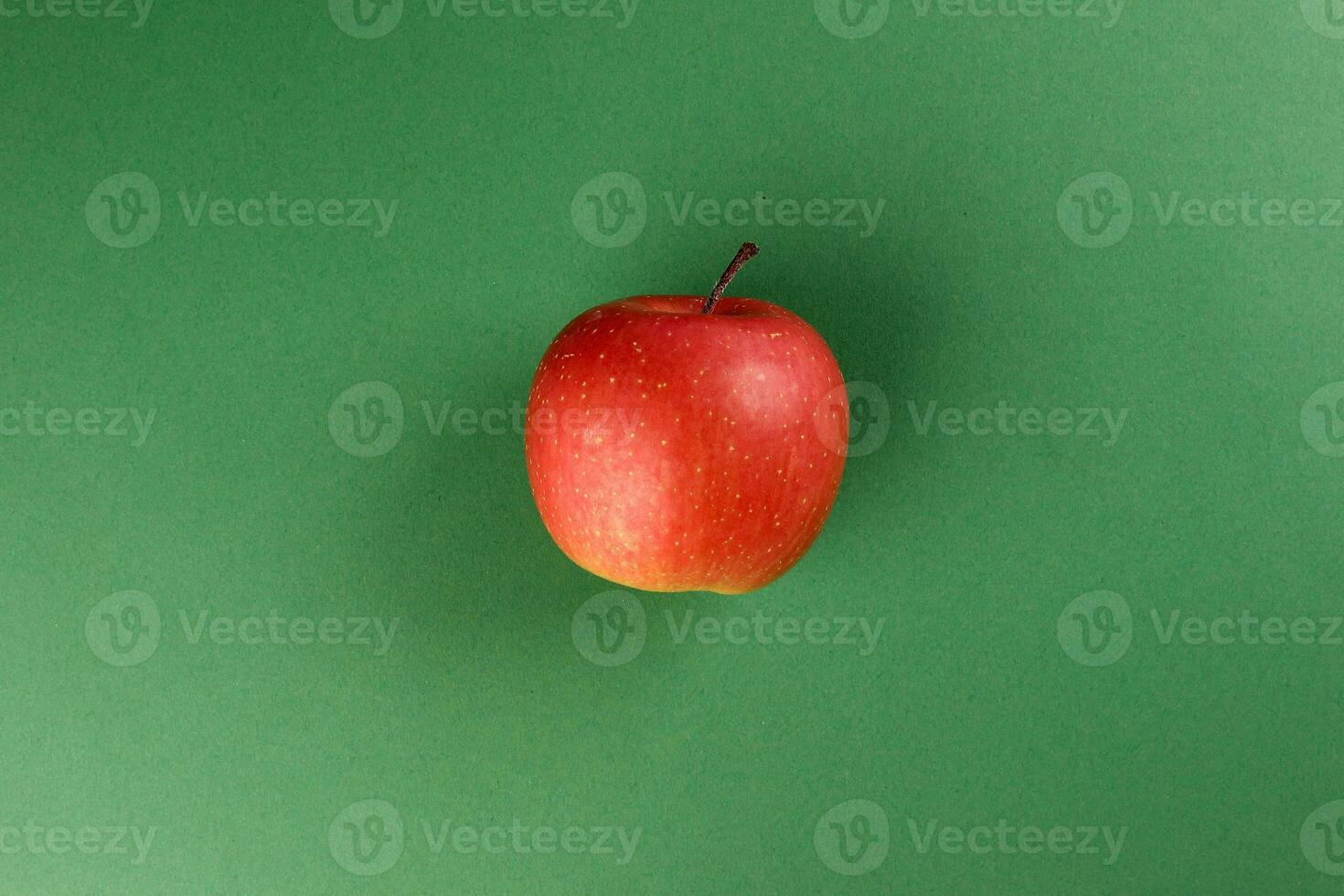 Red  apple on green colour paper background copy space for text photo
