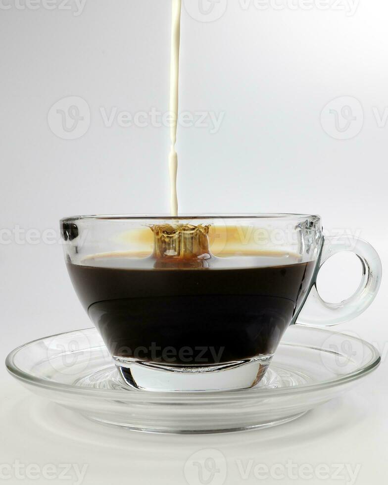 dark Coffee poring white milk dripping splash shadow liquid swirl in glass cup saucer on white background photo