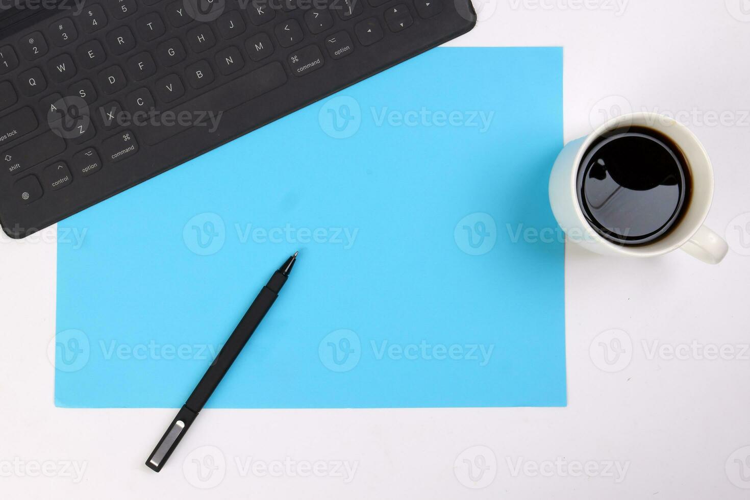 Black computer keyboard coffee cup pen on blue white background top view copy text space photo