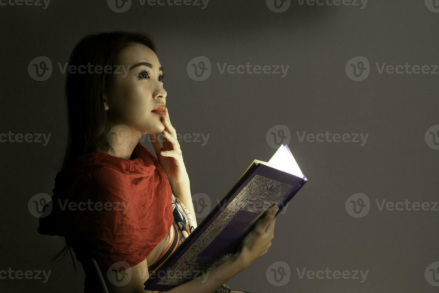 Asian woman opening mystic book box magical light dark background photo