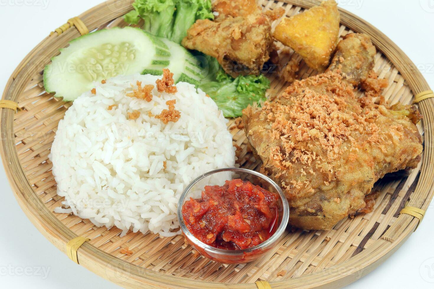 Ayam penyet a East Javanese cuisine smashed fried chicken dish with floss sambal slices of cucumbers fried tofu and tempeh photo