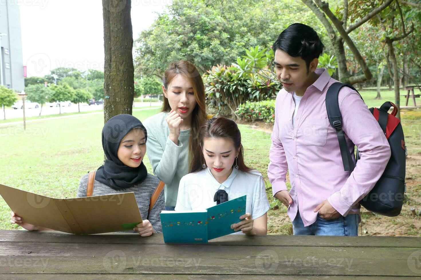 Young asian malay chinese man woman outdoor park  book file folder laptop computer phone sit stand study mingle photo