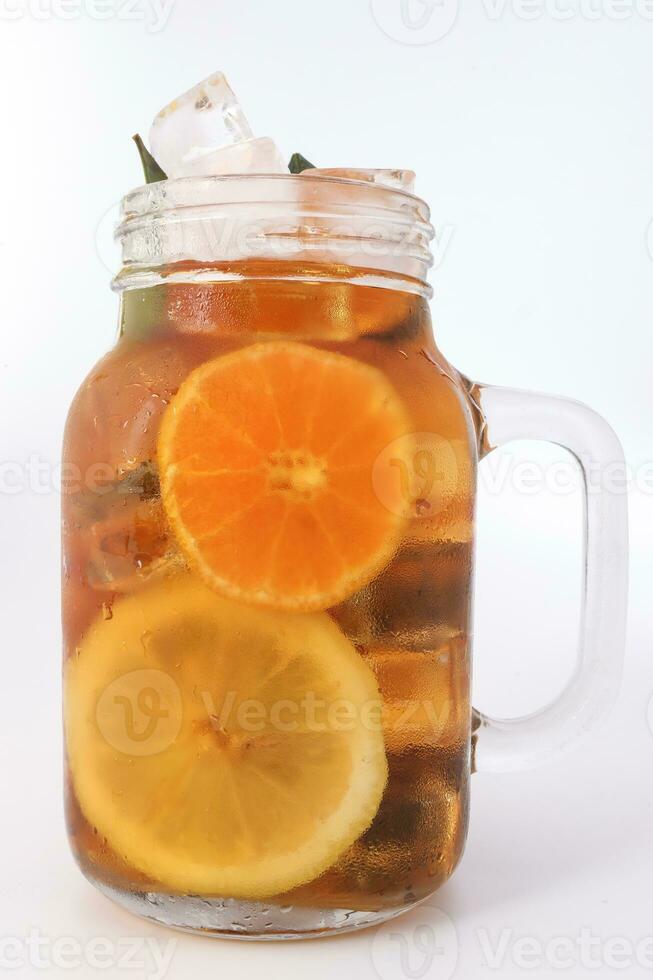 líquido hielo limón naranja té con rebanada verde hoja canela palo en transparente vaso tarro jarra en blanco antecedentes foto