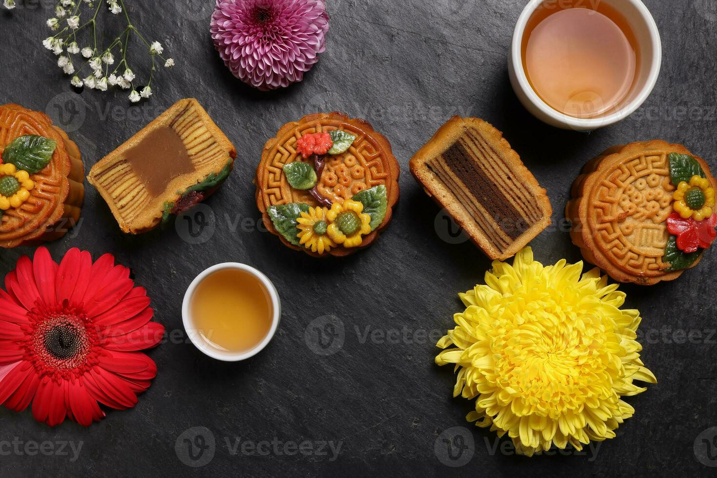 Colourful flower decorated mooncake Chinese mid autumn festival black slate stone background white teacup glass teapot daisy chrysanthemum mum rose baby breath flower red yellow pink purple violet photo