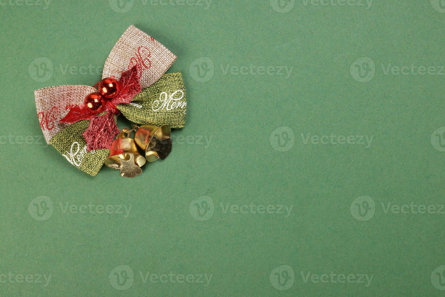 Small Christmas xmas gift bow ribbon Pine Arrangement bell on green background copy text space photo