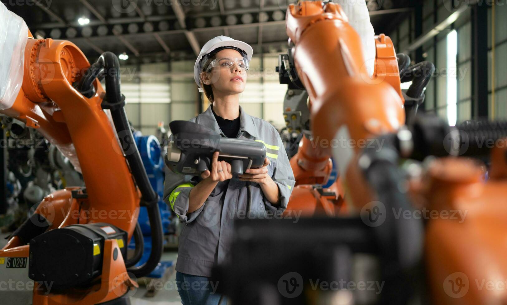 después instalando un programa en el robótico brazo, un hembra ingeniero con un robótico brazo controlador realiza un prueba correr. foto