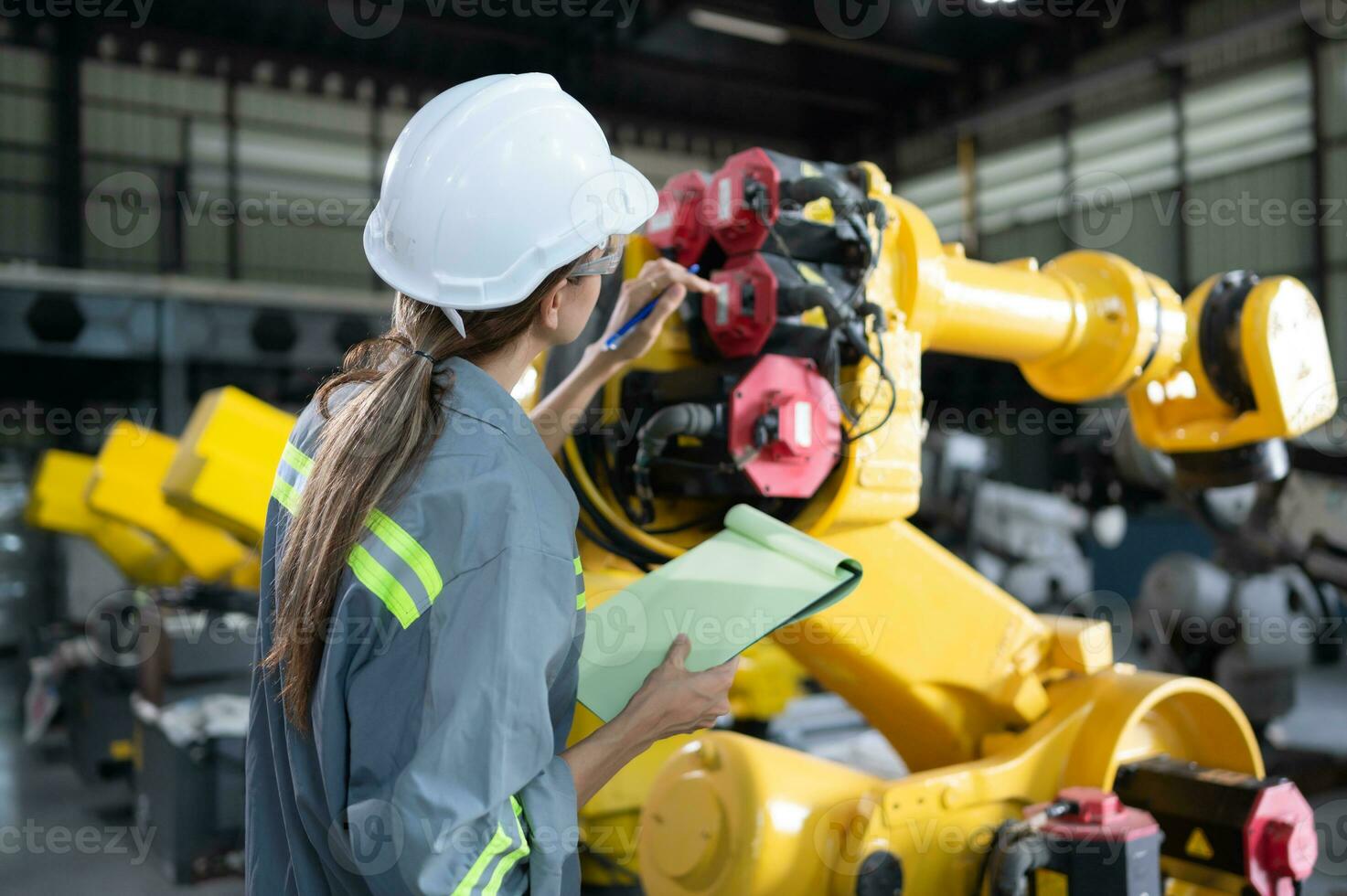 A female engineer checking documented items after installing a program on a robotic arm in a robotic warehouse and test the operation photo