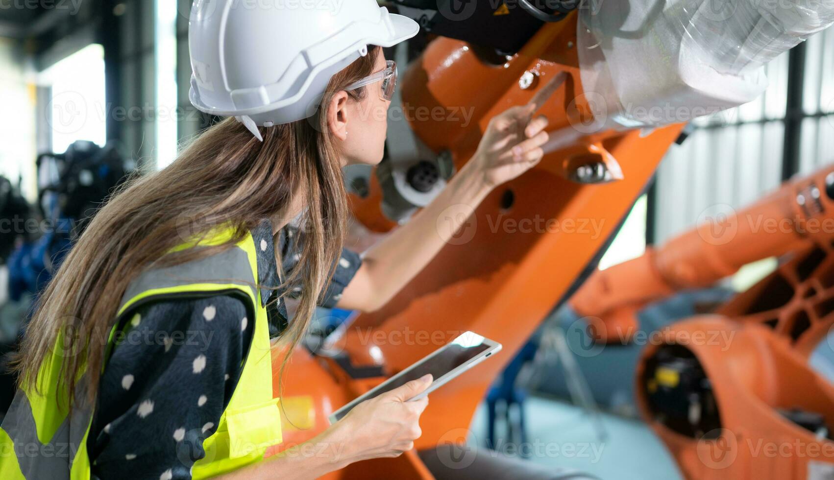 un hembra ingeniero instala un programa en un robótica brazo en un robot depósito. y prueba el operación antes de enviando el máquina a el cliente. foto
