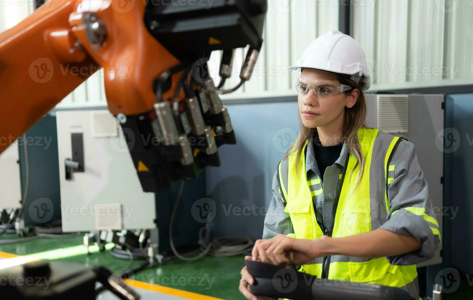 después instalando un programa en el robótico brazo, un hembra ingeniero con un robótico brazo controlador realiza un prueba correr. foto