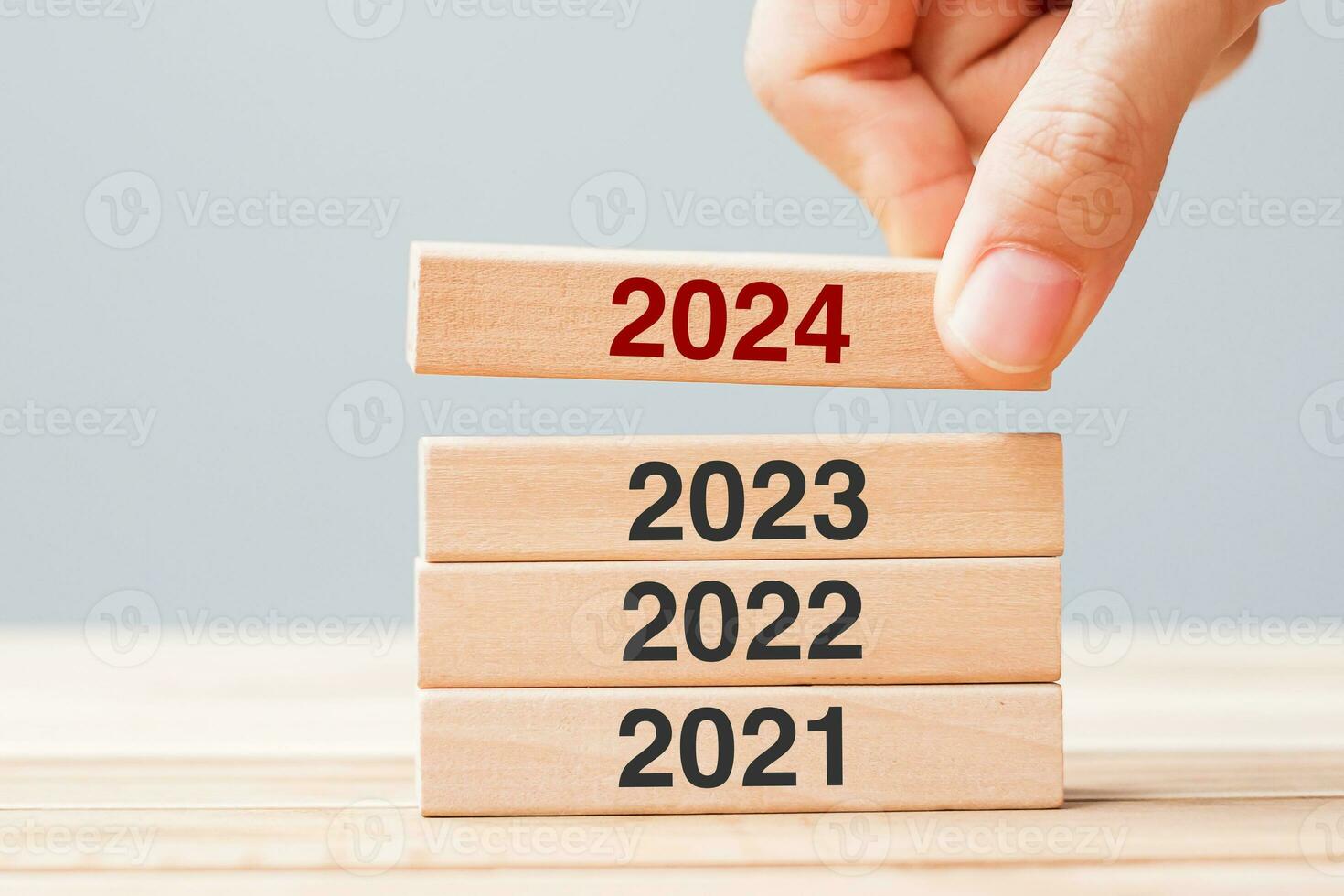 2024 block over 2023 and 2022 wooden building on table background