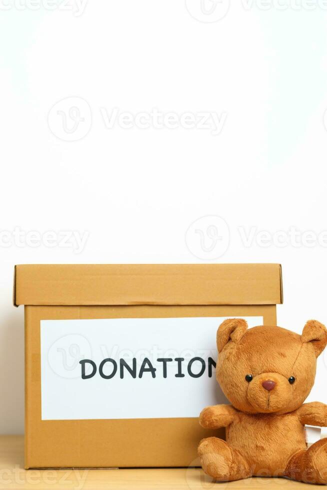 Kid Donation, Charity, Volunteer, Giving and Delivery Concept. Bear doll and Clothes with Donation box at home for support and help poor, refugee and homeless people. Copy space for text photo