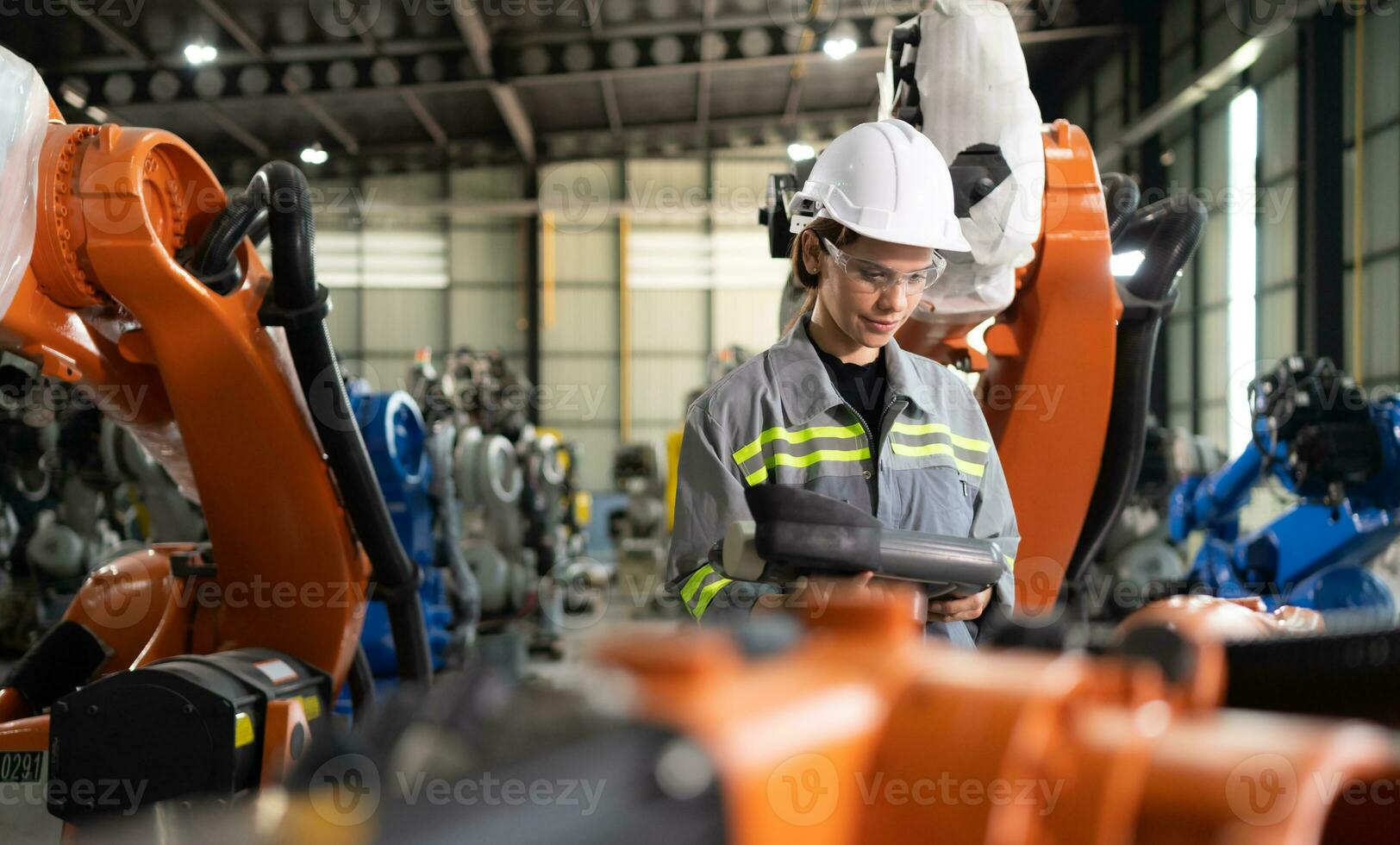 después instalando un programa en el robótico brazo, un hembra ingeniero con un robótico brazo controlador realiza un prueba correr. foto