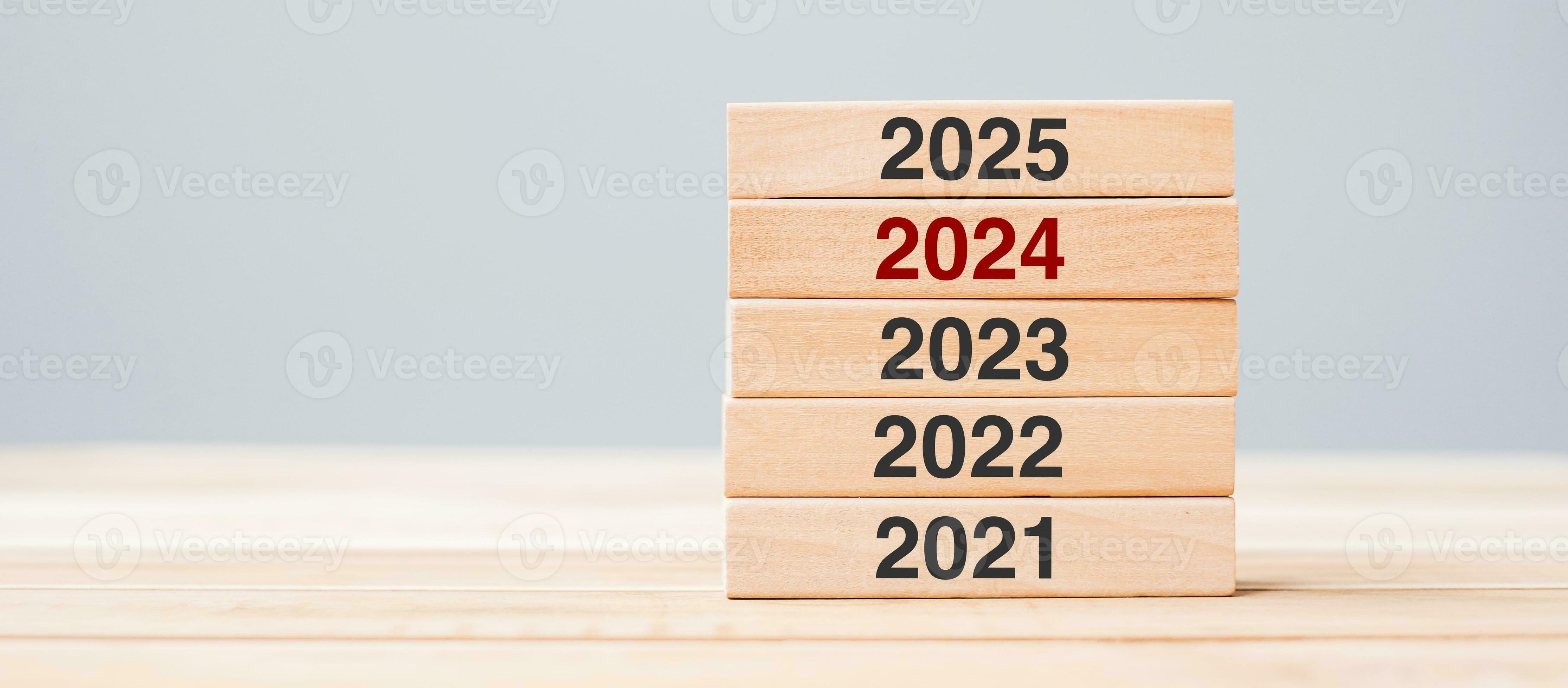 2025 block over 2025 and 2023 wooden building on table background