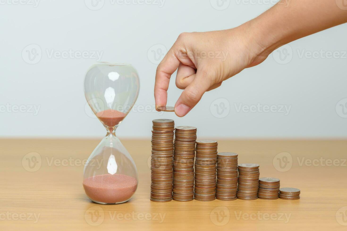 Money Saving for Future Plan, Retirement fund, Pension, Investment, Wealth Business and Financial concepts. hand putting coin on money stack with sandglass photo