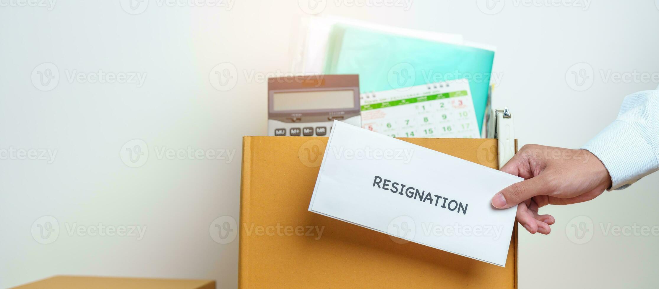 Resignation, Layoff, Unemployment, Dismiss, Job quit, Jobless and Farewell concept. Businessman holding letter of Resign contract with documents cardboard box at office photo