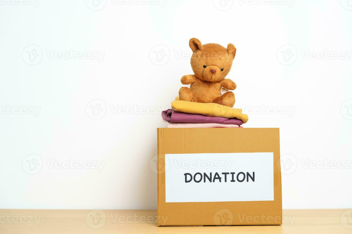 Kid Donation, Charity, Volunteer, Giving and Delivery Concept. Bear doll and Clothes with Donation box at home for support and help poor, refugee and homeless people. Copy space for text photo