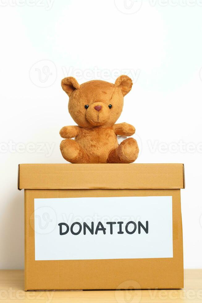 Kid Donation, Charity, Volunteer, Giving and Delivery Concept. Bear doll and Clothes with Donation box at home for support and help poor, refugee and homeless people. Copy space for text photo