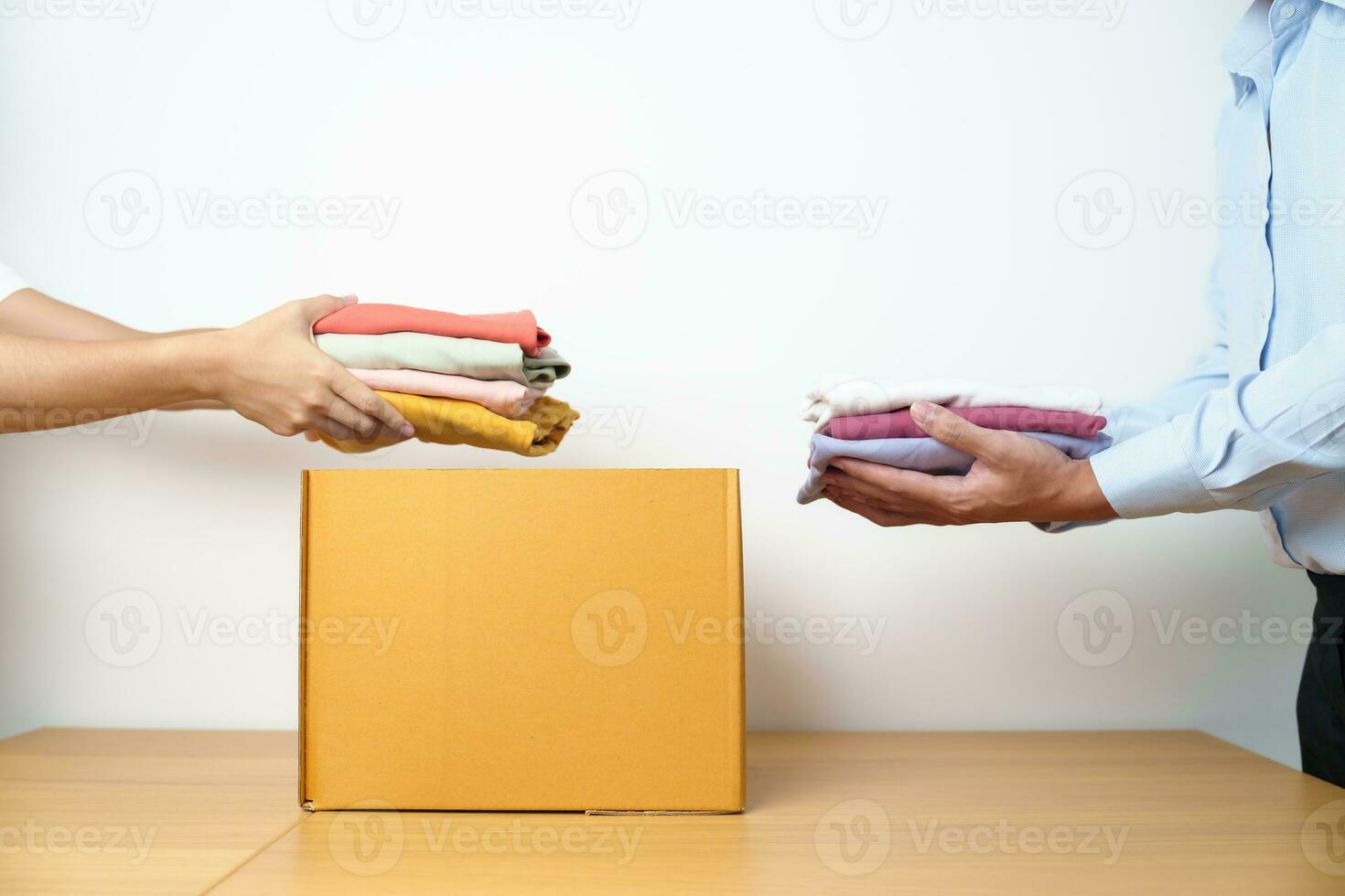 Donation, Charity, Volunteer, Giving, Delivery and Home Moving Concept. Hand holding Clothes into cardboard box at home for support and help poor, refugee and homeless people. Copy space for text photo