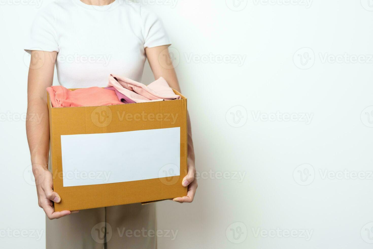 Donation, Charity, Volunteer, Giving, Delivery and Home Moving Concept. Hand holding Clothes into cardboard box at home for support and help poor, refugee and homeless people. Copy space for text photo